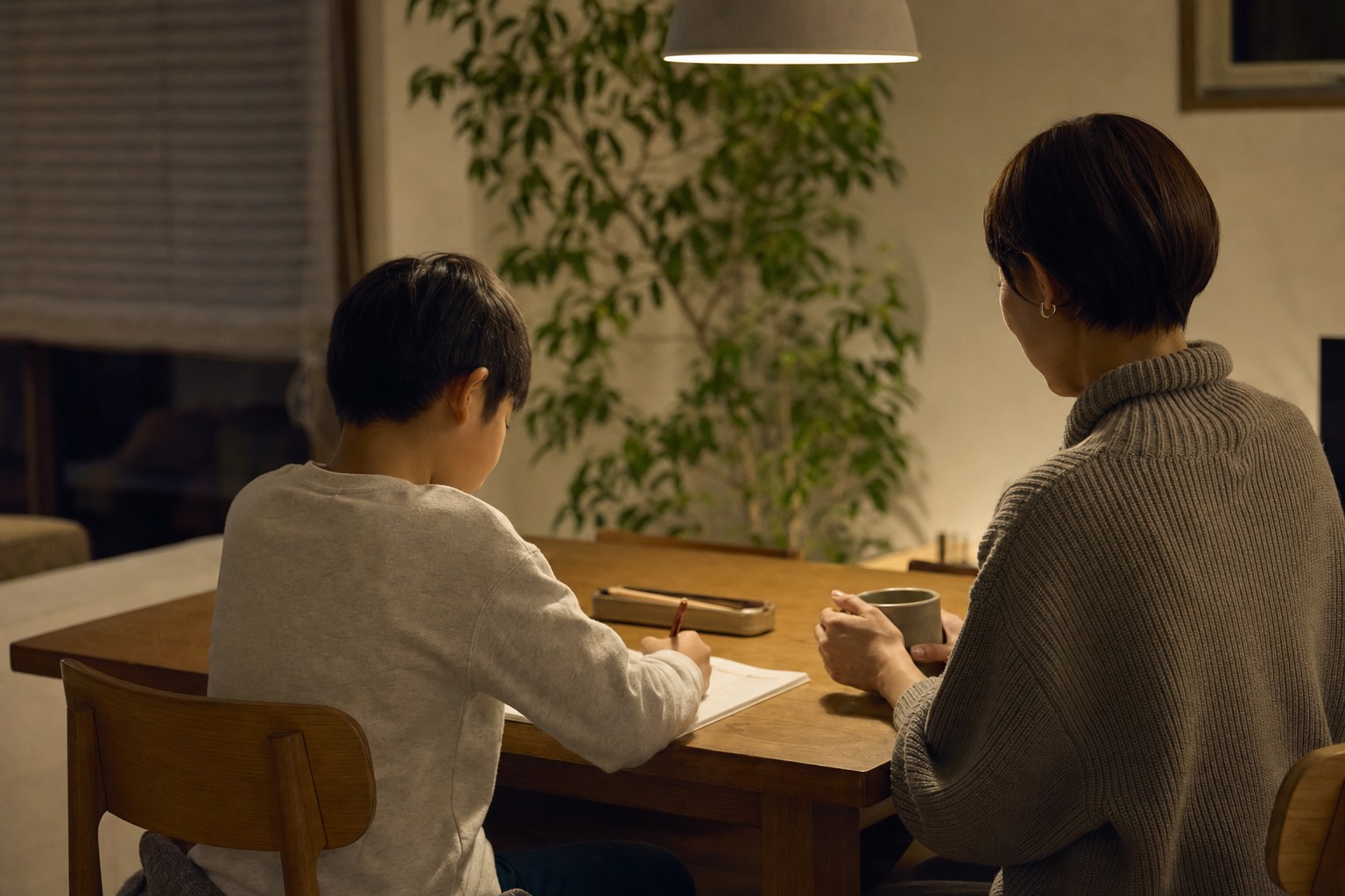 夜のリビングで落ち着いて学習する親子の後ろ姿