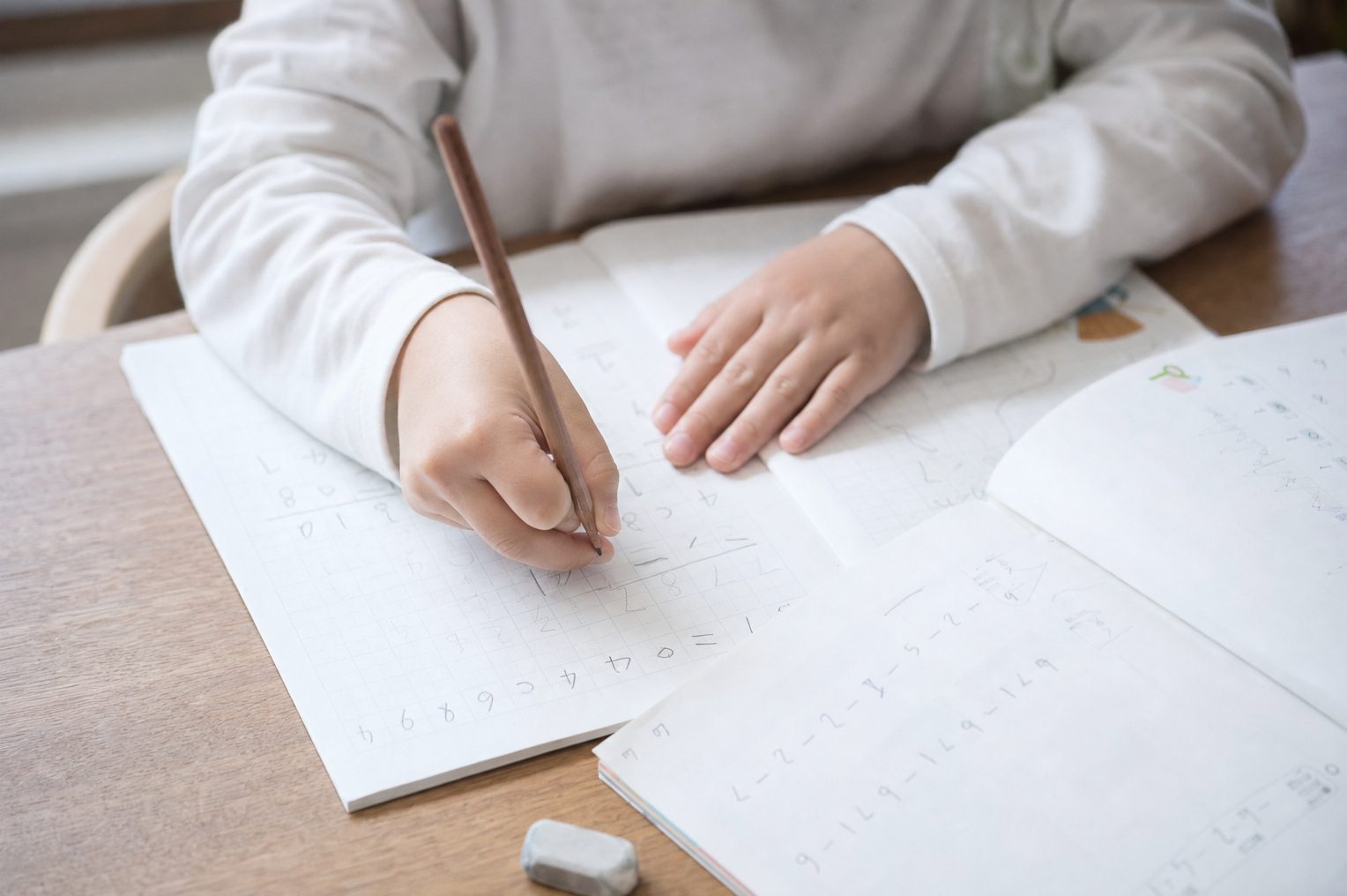 紙の教材とノートで学習する小学生の手元