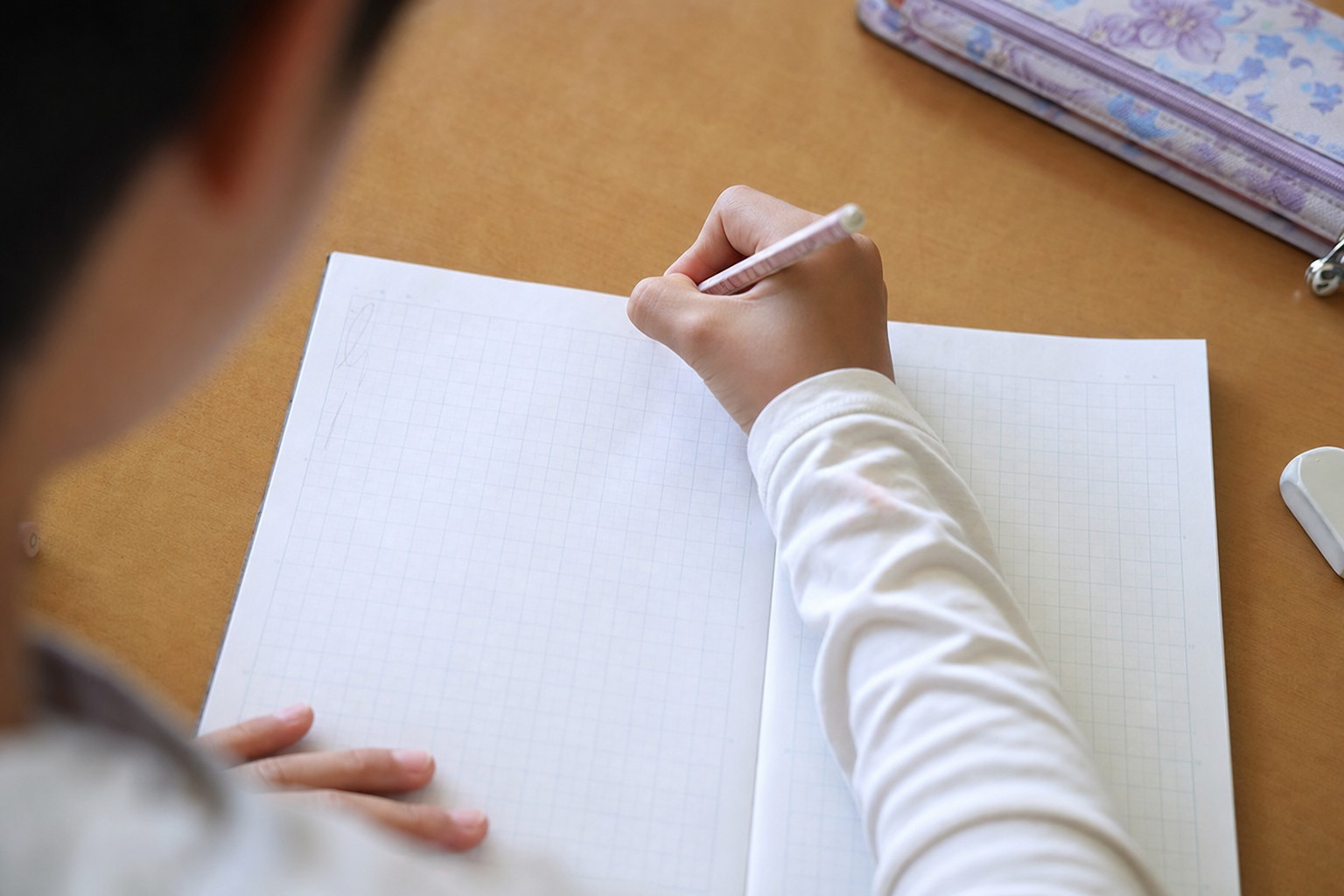 方眼ノートの新しいページに書き始める子どもの手元