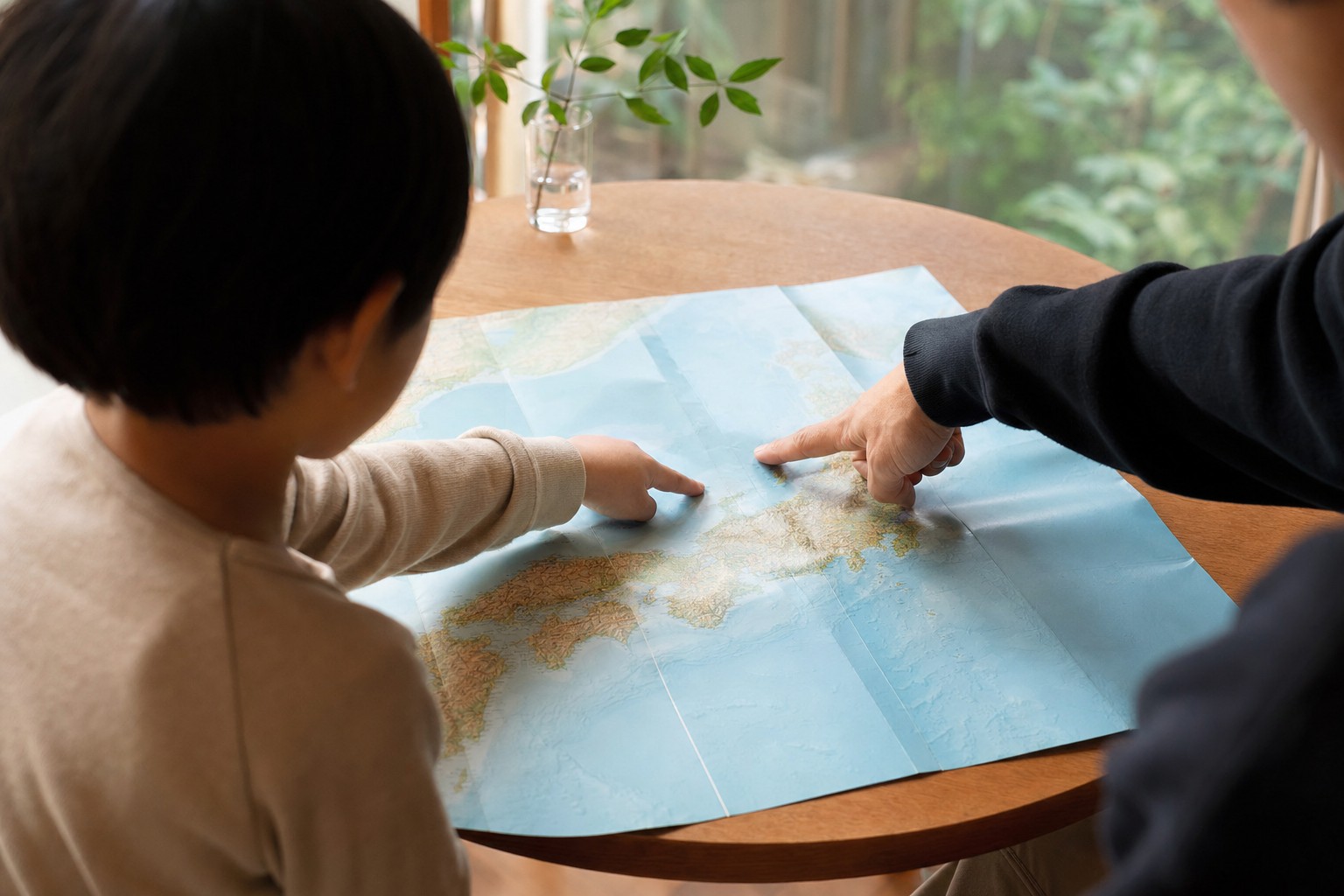 日本地図を広げて指をさす親子の手元