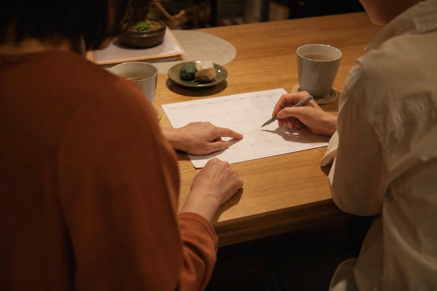 夜のテーブルでカレンダーを見ながら話す夫婦の手元