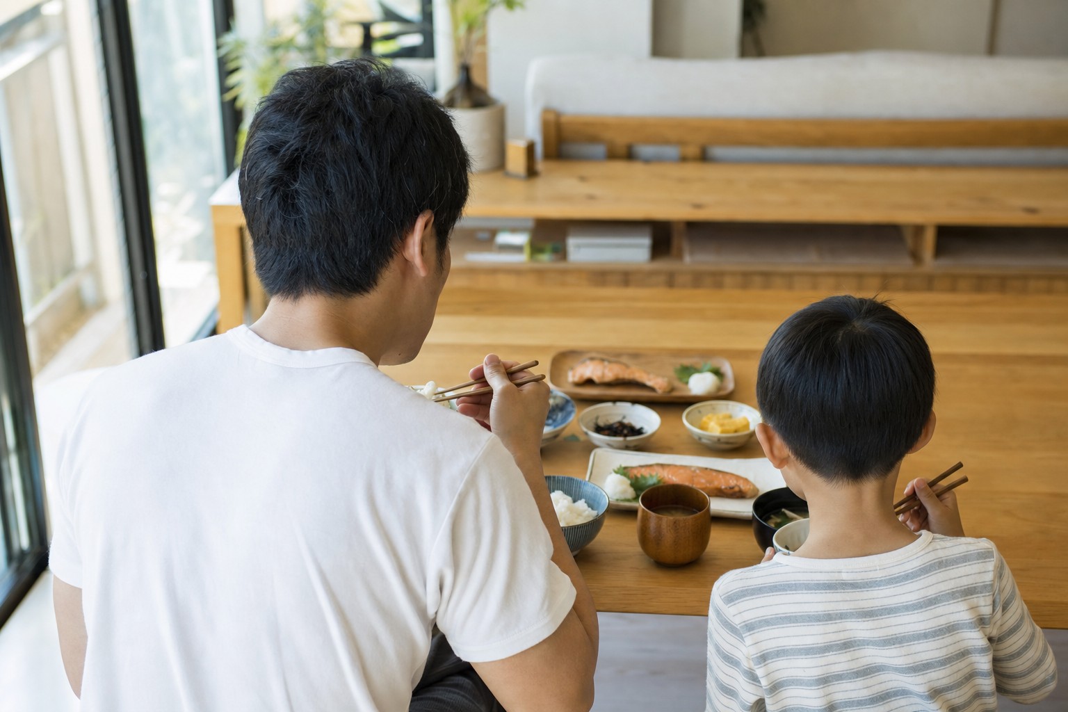 朝の光の中で一緒に朝食をとる親子の後ろ姿
