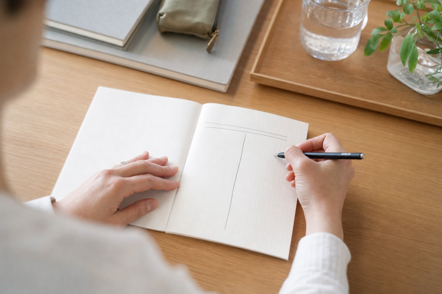 ノートに二分割の表を書き出す親の手元